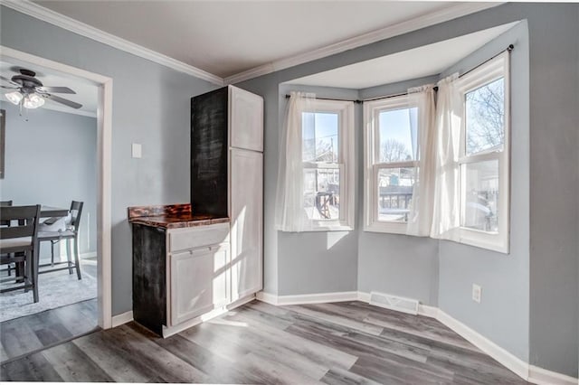 dining area with crown molding, visible vents, ceiling fan, wood finished floors, and baseboards