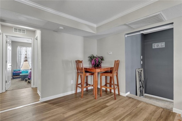 dining room with light wood-type flooring and ornamental molding