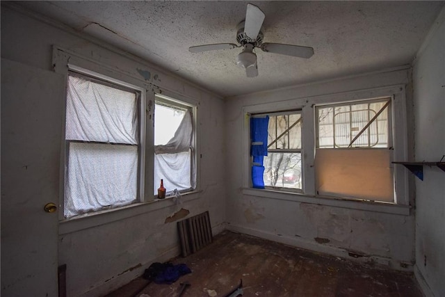 empty room with ceiling fan and a textured ceiling