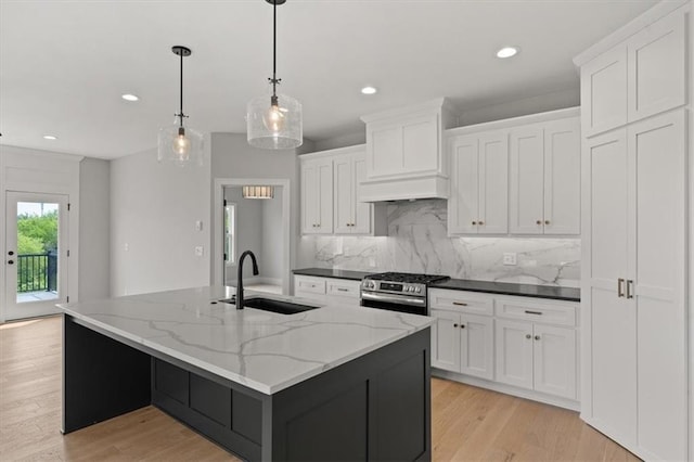 kitchen with white cabinetry, sink, hanging light fixtures, and a center island with sink