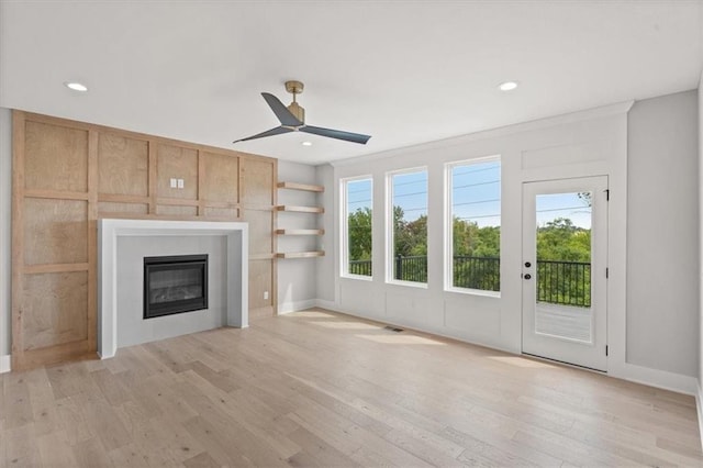 unfurnished living room featuring ceiling fan, light wood-type flooring, and ornamental molding