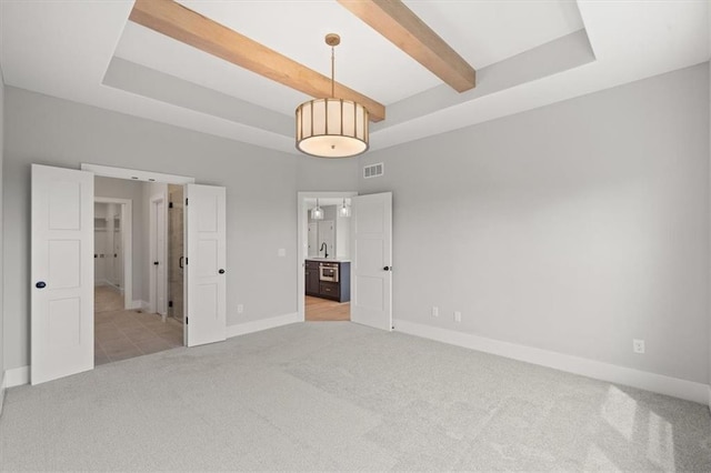 unfurnished bedroom featuring a raised ceiling, sink, and light colored carpet