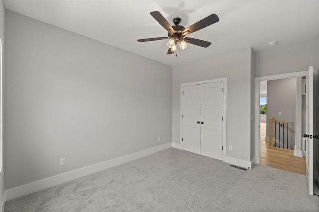 unfurnished bedroom with ceiling fan, a closet, and light carpet