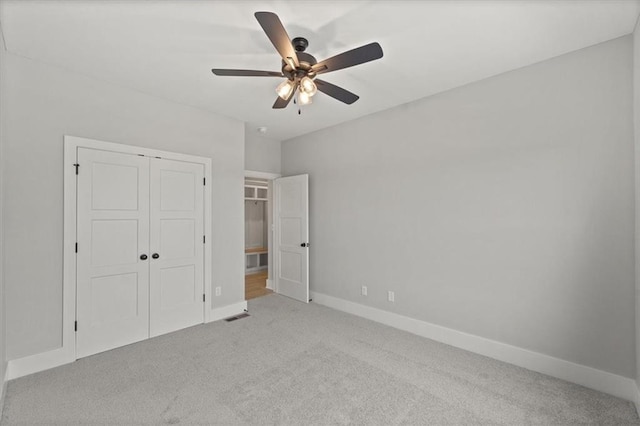 unfurnished bedroom featuring ceiling fan, a closet, and light colored carpet