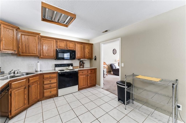 kitchen with black appliances, decorative backsplash, light tile patterned floors, and sink