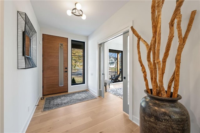 doorway to outside with light hardwood / wood-style flooring and an inviting chandelier