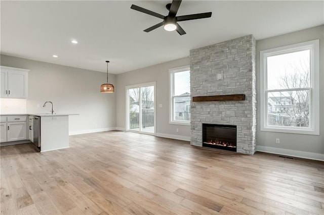 unfurnished living room featuring a fireplace, light hardwood / wood-style floors, and ceiling fan