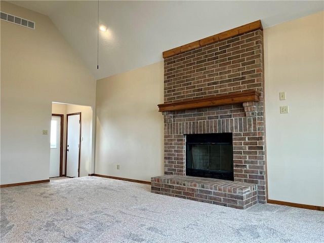 unfurnished living room featuring a brick fireplace, carpet floors, and high vaulted ceiling