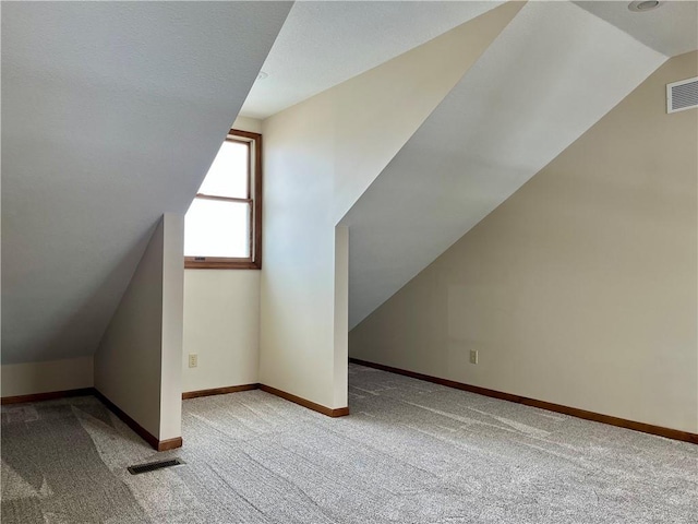 bonus room with lofted ceiling and light colored carpet