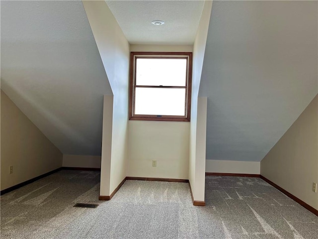 additional living space featuring vaulted ceiling and carpet