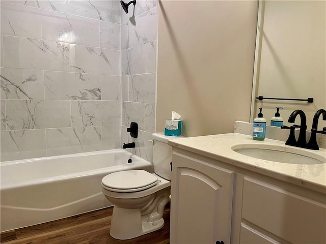 full bathroom featuring hardwood / wood-style flooring, vanity, tiled shower / bath combo, and toilet