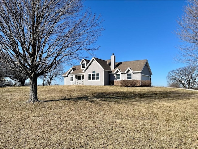 rear view of property with a yard, a chimney, and a garage