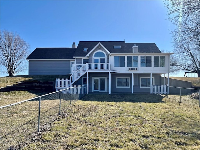 back of property with a lawn, a deck, a fenced backyard, stairway, and a chimney