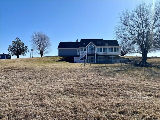 rear view of property with a lawn, stairs, and a deck