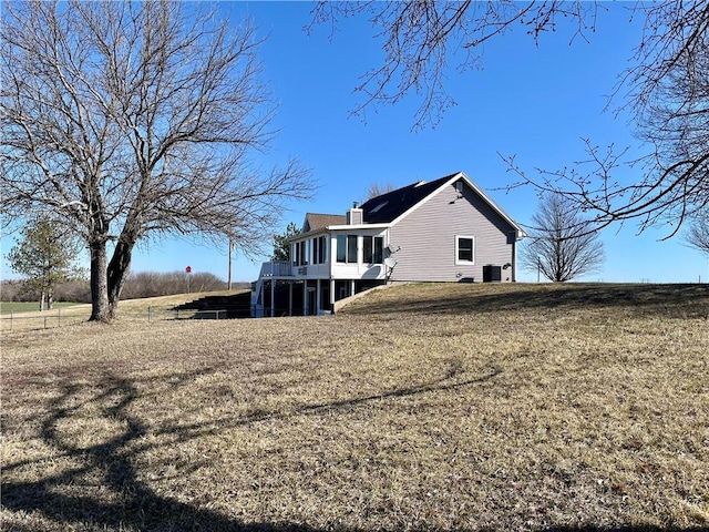 rear view of property featuring a lawn, a deck, and a chimney