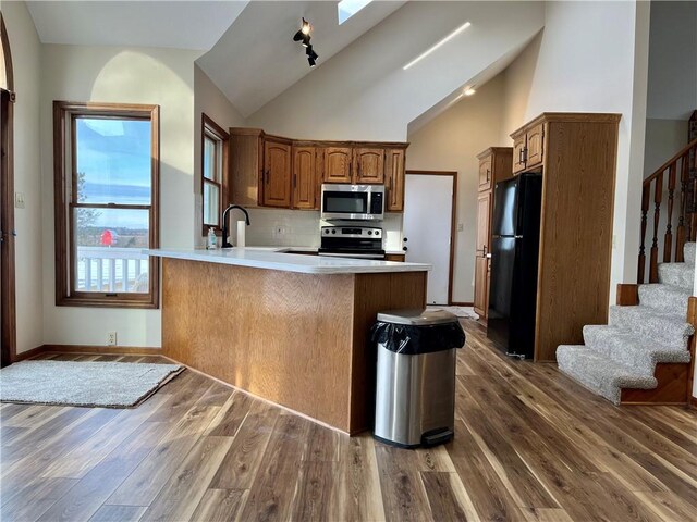 kitchen with dark wood finished floors, appliances with stainless steel finishes, a peninsula, and a sink