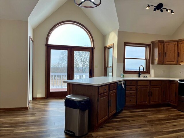 kitchen featuring dishwashing machine, a peninsula, light countertops, dark wood-type flooring, and vaulted ceiling