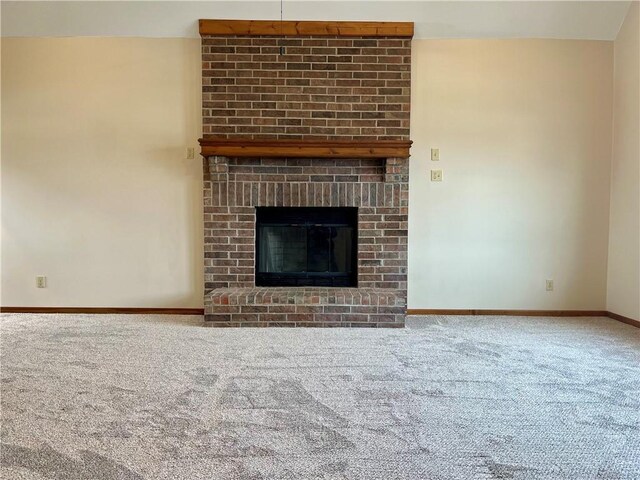 unfurnished living room with a brick fireplace, carpet, and baseboards