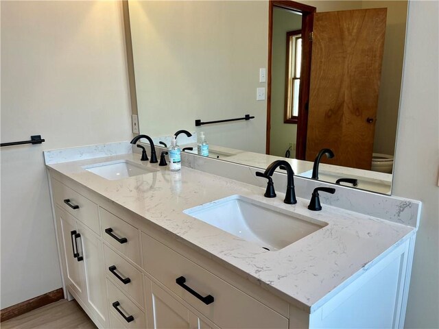 bathroom featuring double vanity, baseboards, and a sink