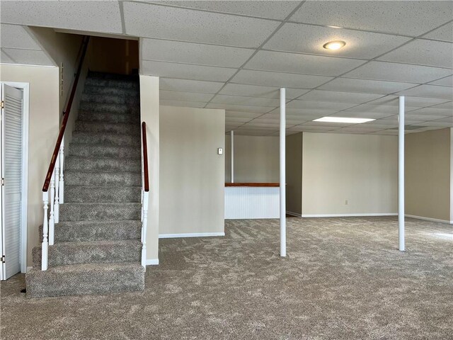 finished basement featuring stairs, carpet flooring, baseboards, and a drop ceiling