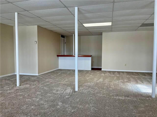 finished below grade area with a drop ceiling, baseboards, and carpet floors