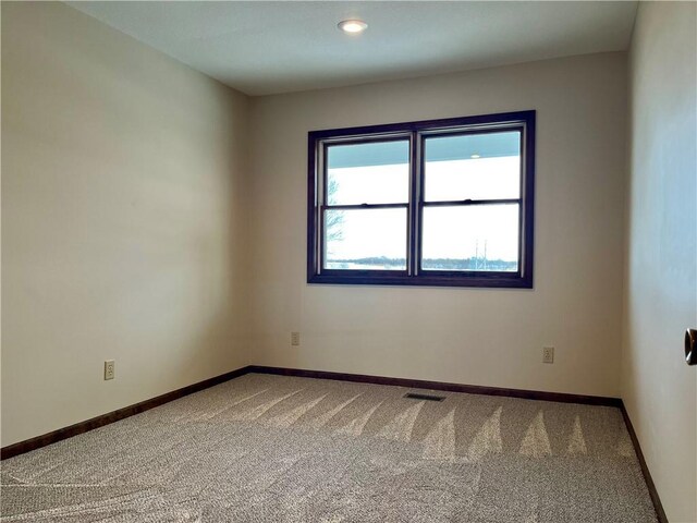 empty room with carpet, visible vents, and baseboards