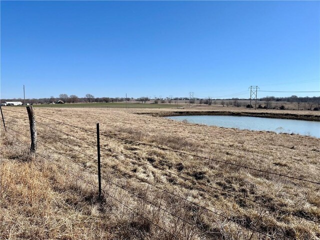 view of yard featuring a water view, a rural view, and fence