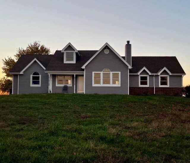 cape cod-style house featuring a front lawn and a chimney