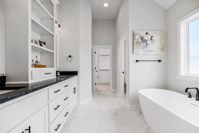 bathroom featuring a bathing tub, vanity, toilet, and a healthy amount of sunlight