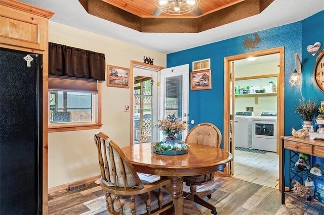 dining area with wood-type flooring, washer and dryer, and a tray ceiling