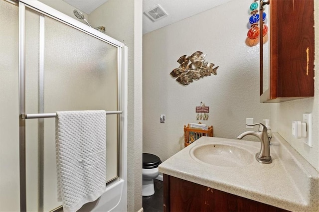 full bathroom with enclosed tub / shower combo, vanity, and toilet