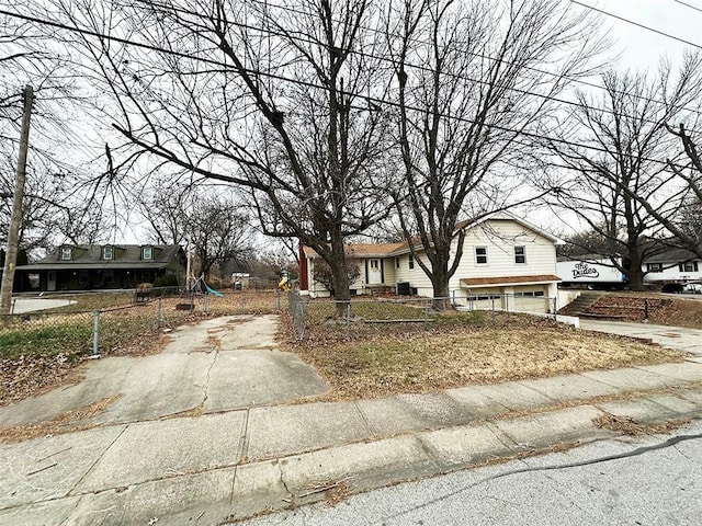 view of front of property featuring a garage, concrete driveway, and a fenced front yard