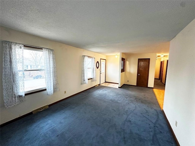 unfurnished room with dark colored carpet and a textured ceiling