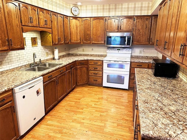 kitchen featuring light stone countertops, sink, light hardwood / wood-style floors, white appliances, and decorative backsplash