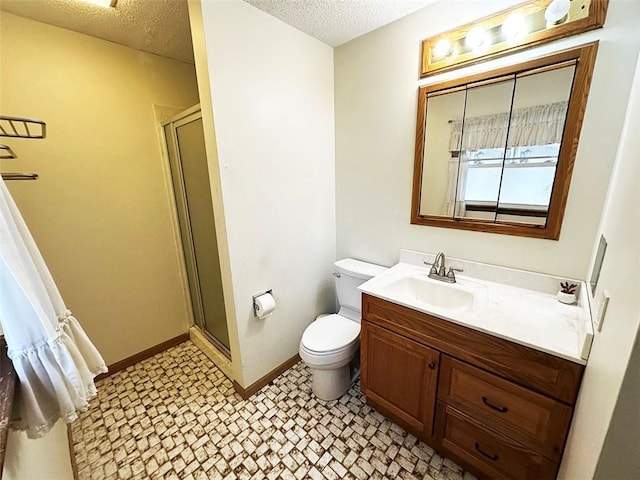 bathroom featuring vanity, a textured ceiling, toilet, and a shower with shower door