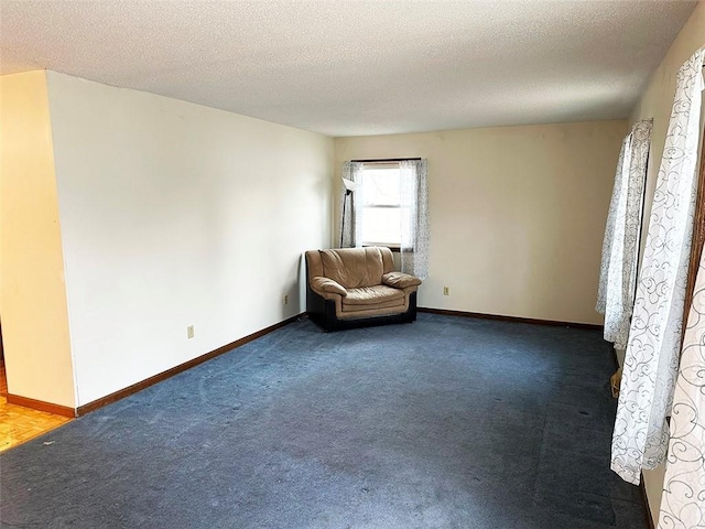 unfurnished room with a textured ceiling and dark colored carpet