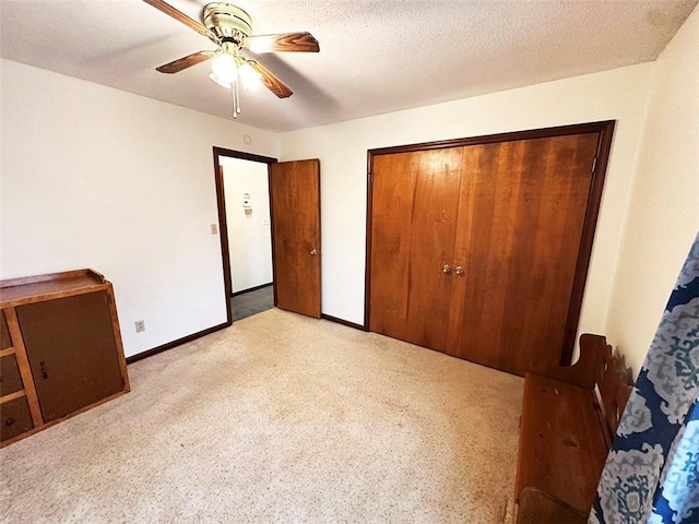 unfurnished bedroom with a textured ceiling, ceiling fan, light carpet, and a closet