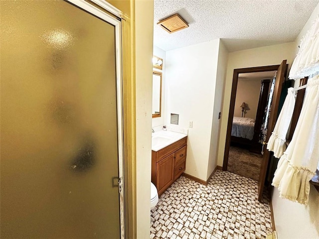 bathroom featuring a shower with door, vanity, a textured ceiling, and toilet