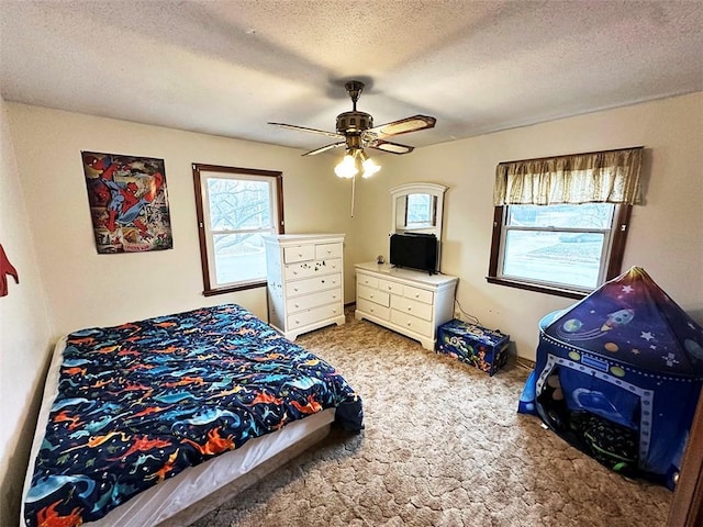 carpeted bedroom featuring ceiling fan, a textured ceiling, and multiple windows