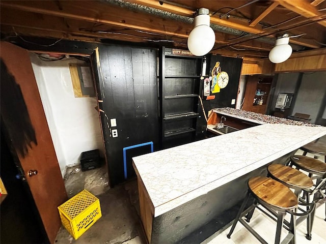 kitchen featuring a kitchen bar, wooden walls, and sink