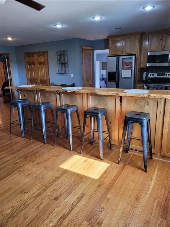 bar with stainless steel appliances and light hardwood / wood-style flooring