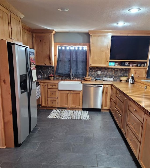 kitchen with decorative backsplash, sink, a textured ceiling, and appliances with stainless steel finishes