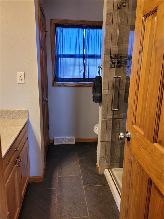 bathroom featuring tile patterned flooring, vanity, toilet, and an enclosed shower