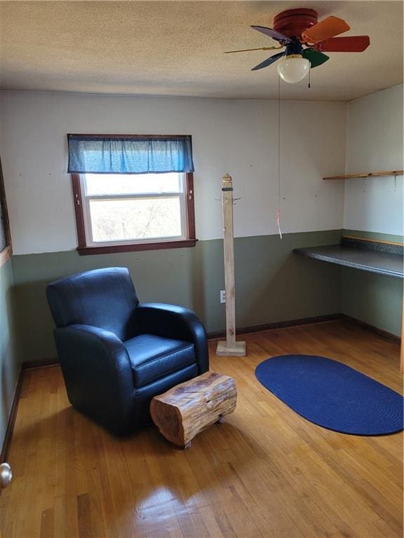 sitting room with wood-type flooring, a textured ceiling, and ceiling fan