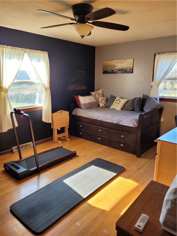 bedroom with multiple windows, wood-type flooring, and ceiling fan