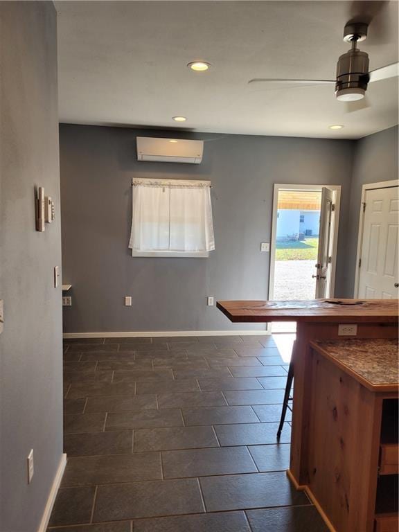 interior space with a kitchen breakfast bar, ceiling fan, and a wall mounted air conditioner