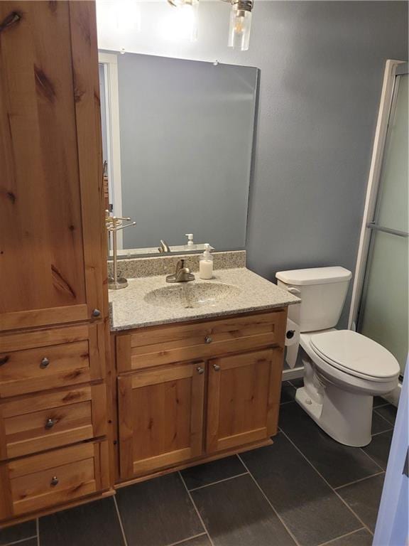 bathroom with tile patterned floors, walk in shower, vanity, and toilet