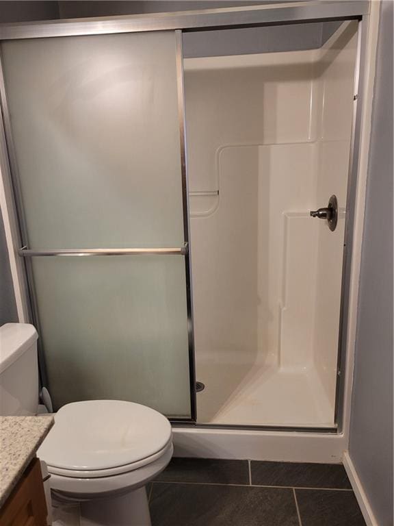 bathroom featuring tile patterned flooring, vanity, toilet, and an enclosed shower