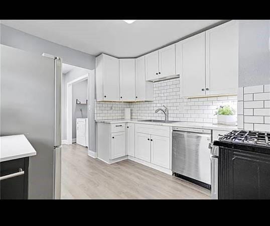 kitchen featuring decorative backsplash, sink, white cabinets, and appliances with stainless steel finishes