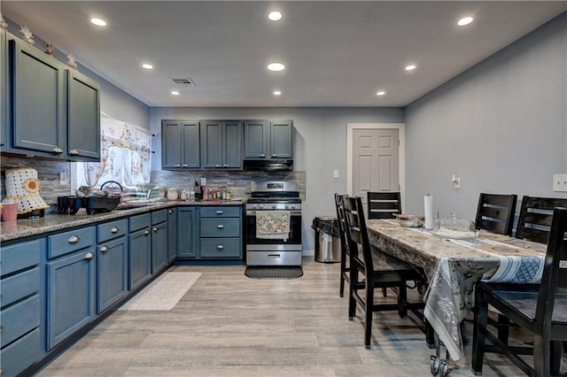 kitchen with decorative backsplash, light wood-type flooring, extractor fan, sink, and stainless steel stove